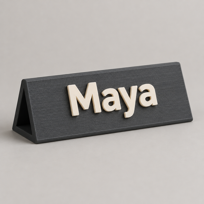 Custom 3D printed desk name plate with raised warm white lettering on a charcoal base
